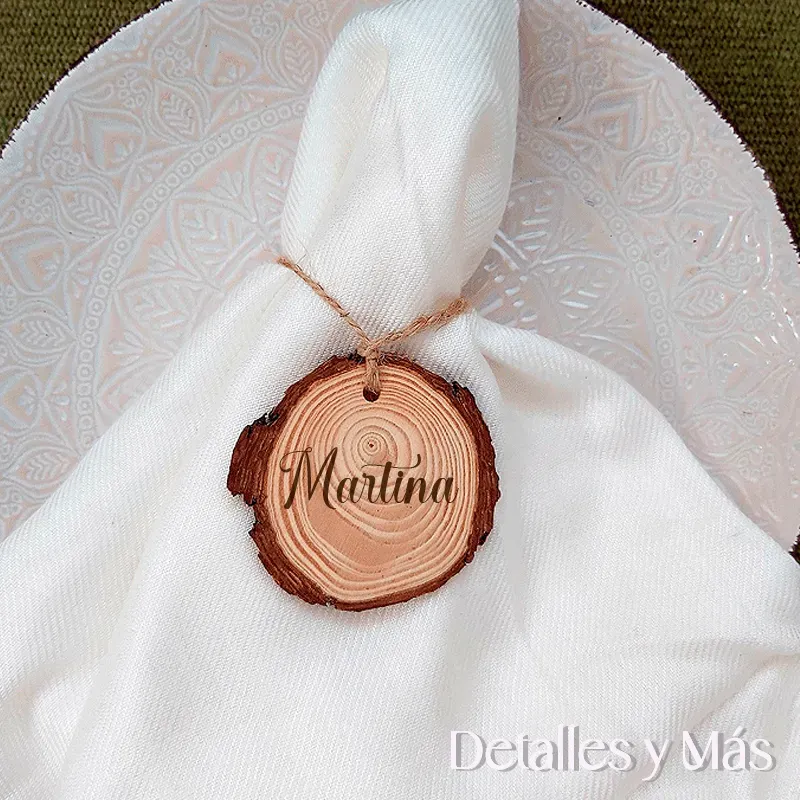 Rodaja de madera con nombre del comensal o invitado para usar como marcasitios en una mesa de boda